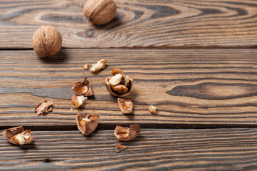 Lot of raw walnuts whole and broken strewn on old weathered wooden table on kitchen. Copy space for your text