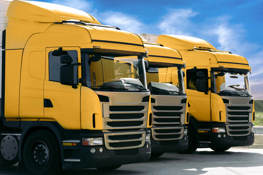three yellow trucks of a transporting company parked in row in the parking lot. trucking and logistics