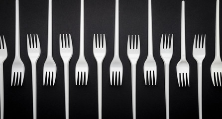 Disposable white plastic fork on a black background, abstraction, top view