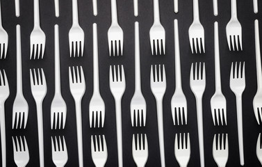 Pattern of white disposable forks on black background, abstraction