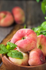 Fig peach in a wooden bowl. Flat peach