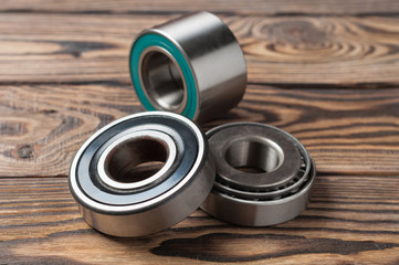 Set of three dirty glossy metal bearings on old weathered wooden table in workshop