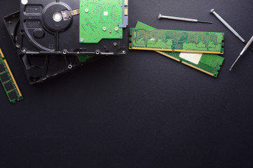 Isolated hard drives, RAM and a set of screwdrivers for computer repair on a black matte background. The concept of data storage and PC repair