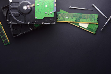 Isolated hard drives, RAM and a set of screwdrivers for computer repair on a black matte...