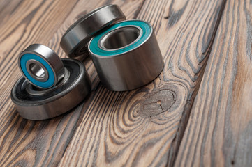 Set of four dirty glossy metal bearings on old weathered wooden table in workshop. Copy space for...