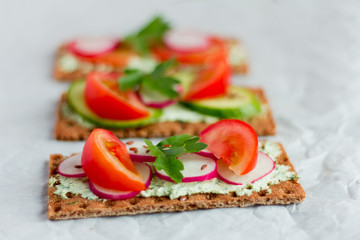 Delicious diet sandwiches with cottage cheese with herbs and vegetables on a white background