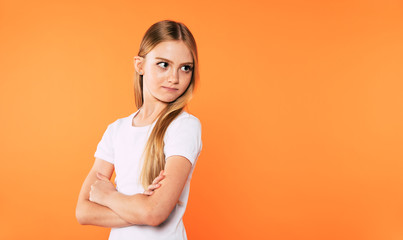 Obraz premium Little cute blonde girl with crossed arms looks away isolated on yellow background.