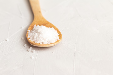 large sea salt in a wooden spoon on grey background. Food ingredients isolated