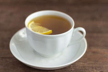 a Cup of herbal tea with a slice of lemon on a wooden background