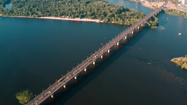Drone view 4K Flying right above the bridge over which the cars are traveling the camera looks down at the water and the bridge
