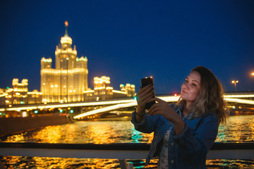 Woman tourist taking pictures on mobile phone during the trip in Moscow. Evening illumination....