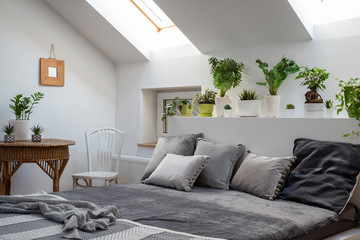 Bedroom interior in the attic with white furniture and double bed with pillows in scandinavian...