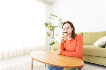 家でコーヒーを飲む若い女性