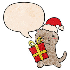cute cartoon cat carrying christmas present and speech bubble in retro texture style