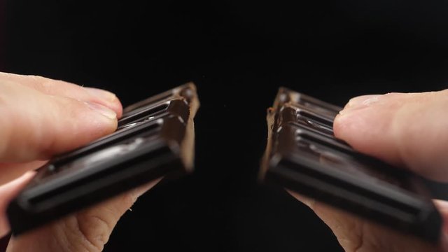 Hands break a bar of chocolate. Slow-motion