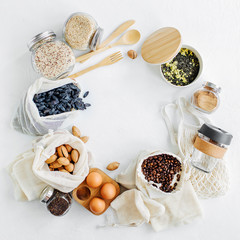 Nuts, dried fruits and  groats  in eco cotton bags and glass jars on white table in the kitchen. Zero Waste Food Shopping.  Waste-free living