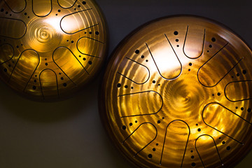 Two golden hang drums small and big on a black background, top view