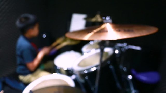 wooden drumsticks in hands of Asian kid wearing blue  t-shirts to learning and play drum set in music room, the concept of musical instrument