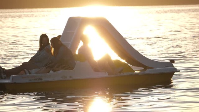 Beautiful seascape sunset with pedal boat silhouette refugee floating on the water with reflection. Pedal boat passing through the sea bay.