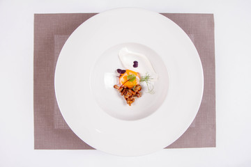 Sous-vide egg yolk, chanterelles and fresh cream on a plate, ready to be poured over with a young sorrel soup