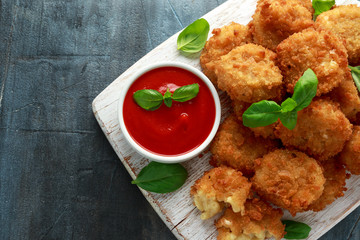 Fried Mac, macaroni and Cheese Bites in breadcrumbs with ketchup sauce on white wooden board