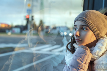 Girl teenager sits on the bus and looks out the window,teenager girl is sitting in the bus looking...