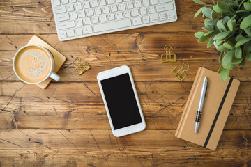 Smartphone mockup template with coffee cup and notebook on wooden table. Top view from above