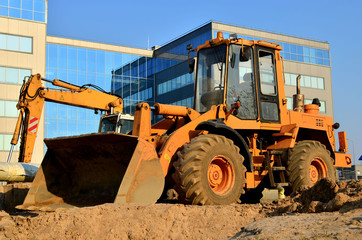 Obraz na płótnie Canvas Wheel loader bulldozer with a bucket on a street in the city during the construction of the road.