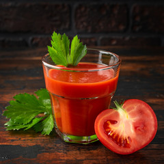 Tomato juice in glass with celery on rustic wooden table