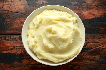 Mashed potatoes in white bowl on wooden rustic table. Healthy food