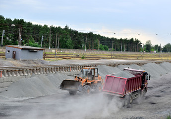 Wheel loader unload gravel and crushed stone in the dump truck. Unloading bulk cargo with of the...
