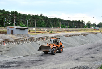 The wheel loader unloads crushed stone in a gravel pit. Unload bulk cargo with of the cargo railway...