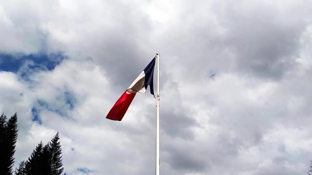 French flag waving and flapping under the cloudy blue sky