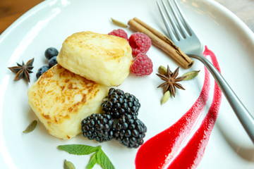 Curd cheesecakes on a plate with berries. Delicious and healthy breakfast. Close-up. Beautiful design dishes.