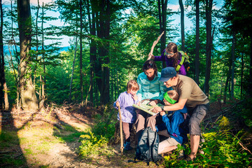 Happy family - father, mother and three daughters -  on a mountain trip in the forest looking at...