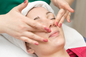 Obraz na płótnie Canvas Face skin care. Beautician applying beauty oil mask on face using brush In spa salon 