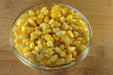 Yellow corn grains in a glass bowl. Steamed corn as a concept of a vegan food.