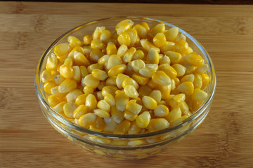 Yellow corn grains in a glass bowl. Steamed corn as a concept of a vegan food.