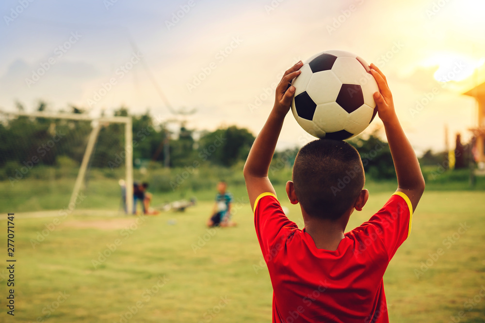 Sticker Action sport outdoors of kids having fun playing soccer football for exercise in community rural area under the twilight sunset sky. Picture with copy space.