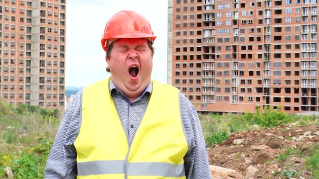 Tired male builder foreman, worker or architect on construction building site yawning