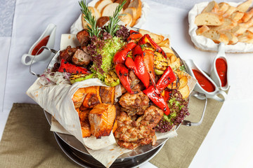 Mixed grill meat, fried vegetables and grilled salmon fish fillets decoration in warm dish. Assorted delicious grilled kebab served with herbs on platter. Restaurant menu plate