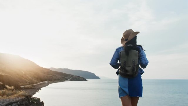 Back view active backpacker female approaching sea admiring amazing seascape from mountain