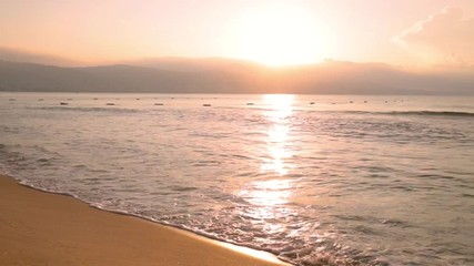 Sunrise over the sea, the waves of the surf rolled on the sandy beach