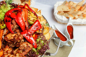 Mixed grill meat, fried vegetables and grilled salmon fish fillets decoration in warm dish. Assorted delicious grilled kebab served with herbs on platter. Restaurant menu plate