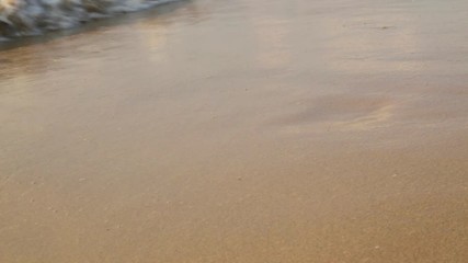 Foaming waves rolled on the sandy beach close up