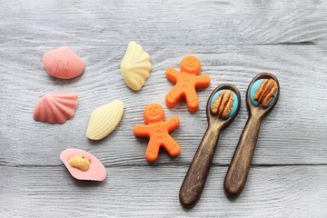 Little chocolate figures. Spoons, little men, shells on wooden background. Sweet art and food.