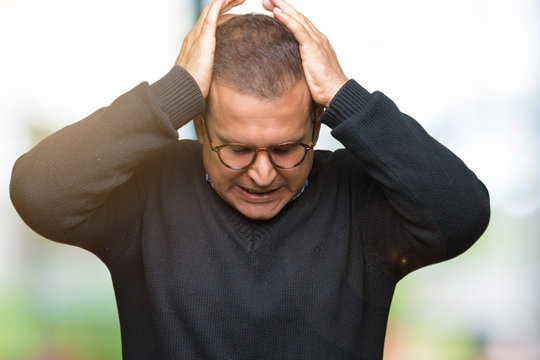 Middle age bussines arab man wearing glasses over isolated background suffering from headache desperate and stressed because pain and migraine. Hands on head.