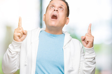 Middle age arab man wearing sweatshirt over isolated background amazed and surprised looking up and pointing with fingers and raised arms.
