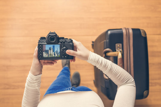 Top view on a girl looking a photos Chicago city on her camera standing with suitcase in the airport. The girl returns home after trip to America.