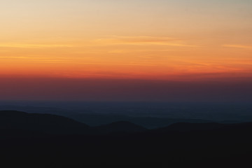 Mountain layer silhouettes after sunset with orange color tones. Harz National Park in Germany